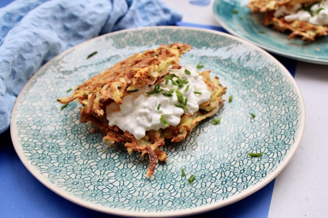 Zdjęcie złocistych i chrupiących gofrów ziemniaczanych serwowanych na płaskim talerzu z serkiem wiejskim